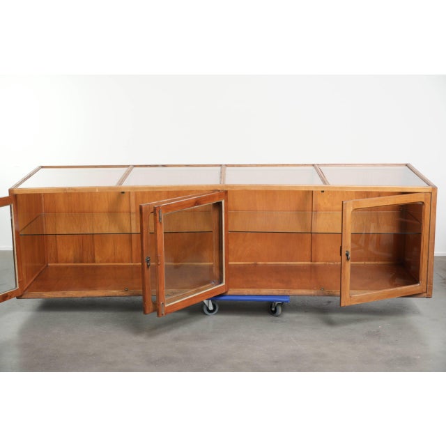 This particularly charming and large vintage wooden counter/display cabinet with 4 doors and glass is a luxurious and...