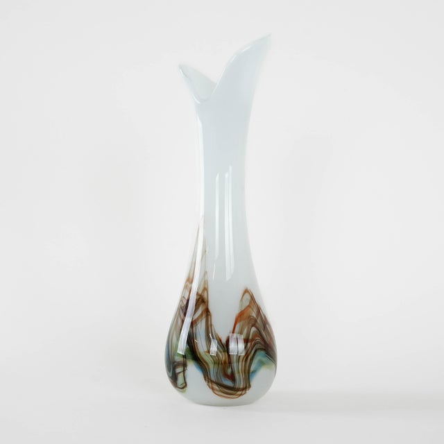 The artistic glass vase was made in the 1970s in Denmark. A slender, sculptural vase made of white glass with...