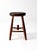 A late 19th-century primitive wood stool with a substantial round seat, gracefully splayed legs, and a distinctive turned...