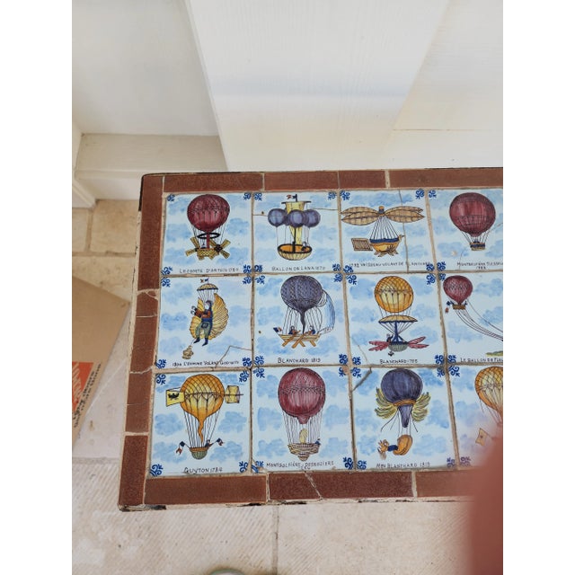 Charming rustic antique tile top table with an iron base. Each tile is painted with a hot air balloon design and there is...