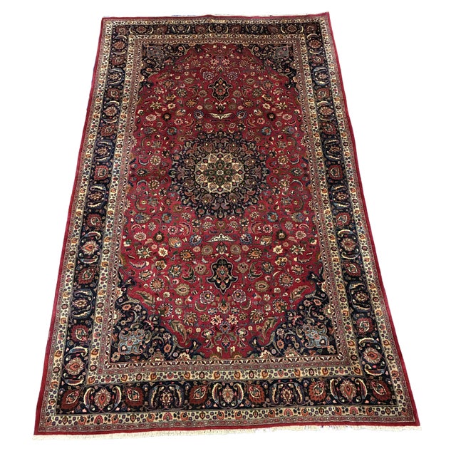 An impressive hand-knotted Persian Kerman rug featuring a richly saturated ruby-red field with an elaborate floral...