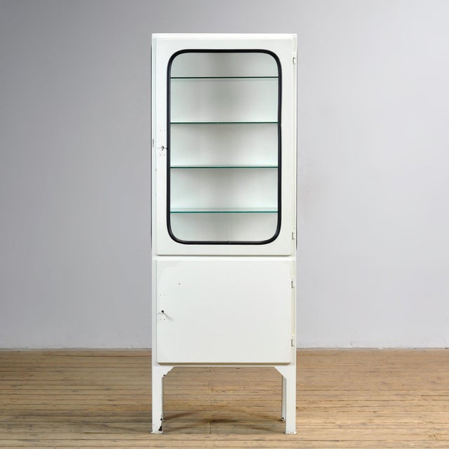 Vintage medicine cabinet from the 1970s, produced in Hungary. This cabinet is made of iron and glass, with the glass held...
