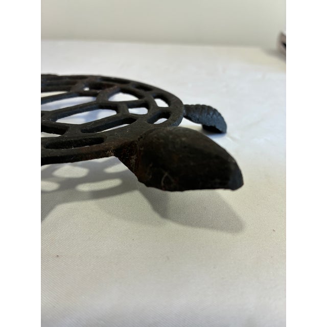 A charming vintage cast iron trivet in the form of a sea turtle, featuring an openwork shell pattern and detailed sculpted...
