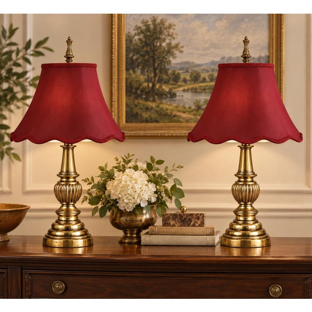 A matched pair of turned solid-brass table lamps with stepped circular bases, tapered necks, and sculptural fluted urn...