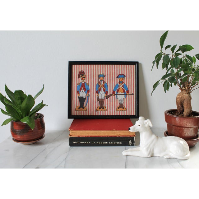 Vintage framed colonial characters wall hanging. No makers mark. Some light age wear to black frame. Ready to hang.