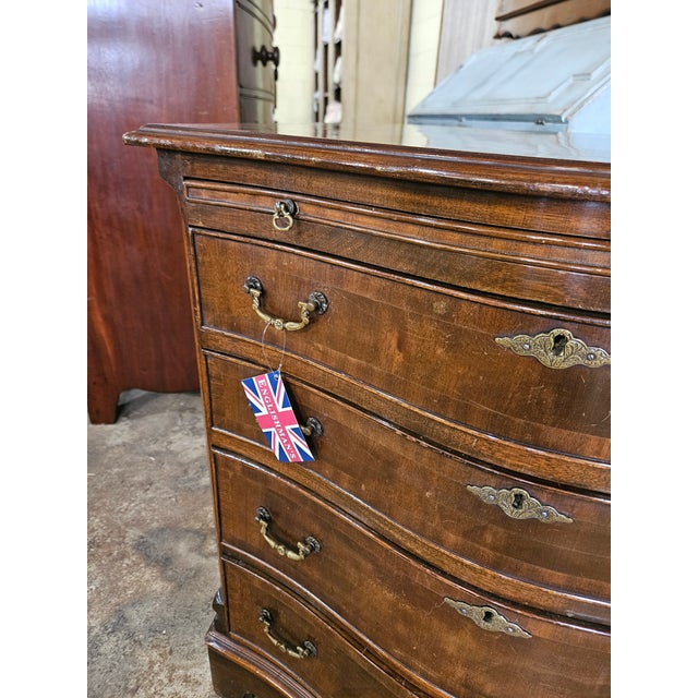 Walnut Crossbanded Serpentine 4 Drawer Chest With Slideand brass handles and escutcheons, all on bracket feet.