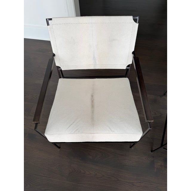These stunning chairs from Oly Studio showcase a mixed-material design featuring premium cream-colored natural hide...