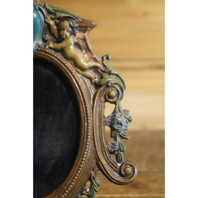 An early frame which is made of heavy metal and colored vaguely, with embellished cherubs and figures in the surround....