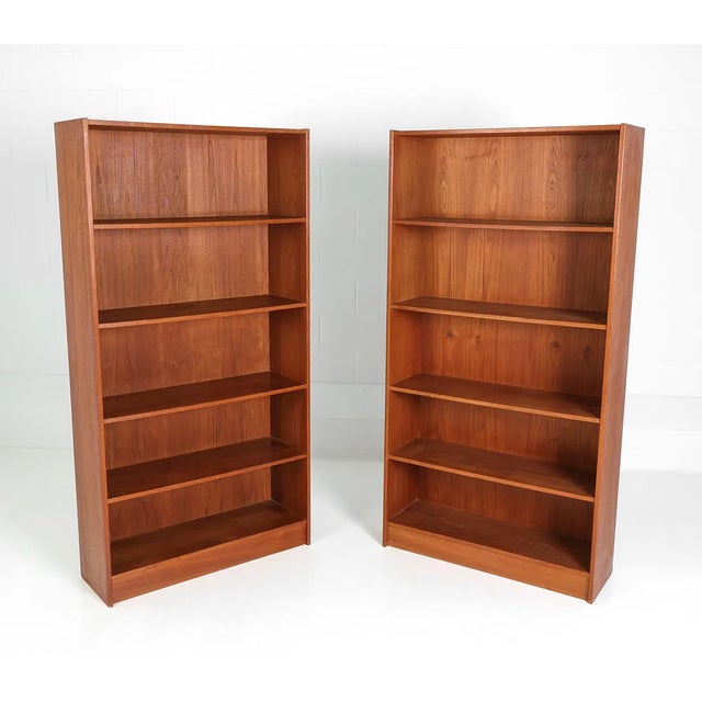 Clean-lined pair of freestanding bookcases in teak, executed in the manner of Sejling Møbelfabrik. Rectangular vertical...