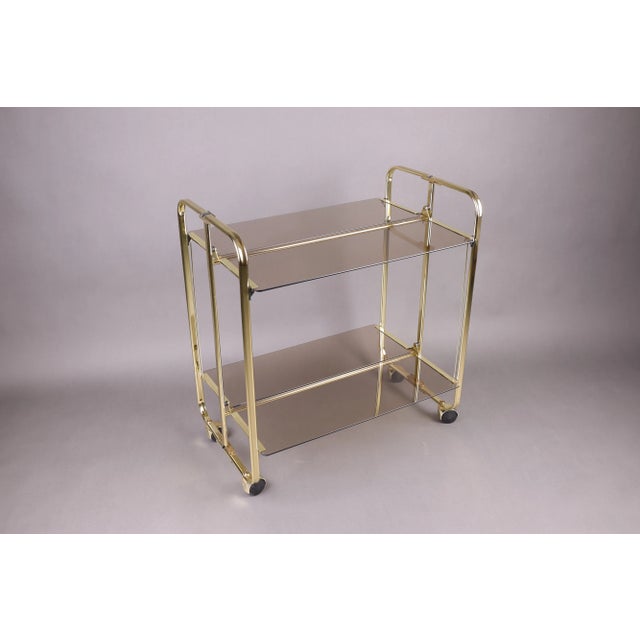 This elegant two-tier serving cart exemplifies 1980s German craftsmanship, blending functionality with timeless Hollywood...