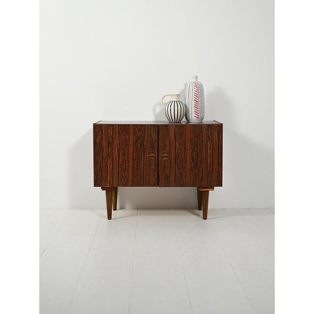 Danish cabinet from the 1950s–1960s, rosewood-effect laminate, hinged doors with recessed handles, and tapered legs. This...