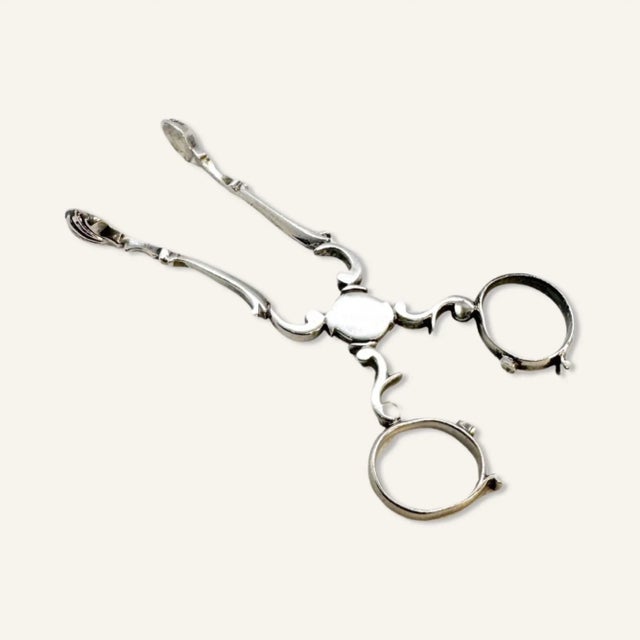 17th century silver sugar scissor tongs with shell termini. Monogram present, but worn and illegible. These sugar tongs...