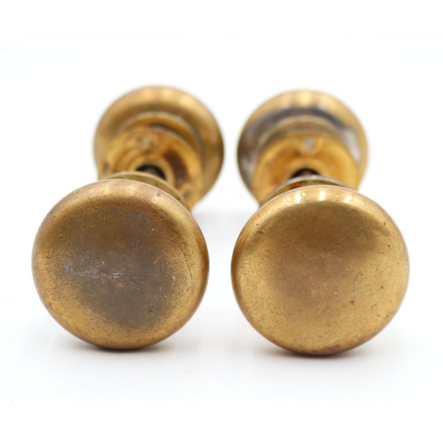 Two classic style passage door knob sets with round brass door knobs and matching brass rosettes. The original mounting...