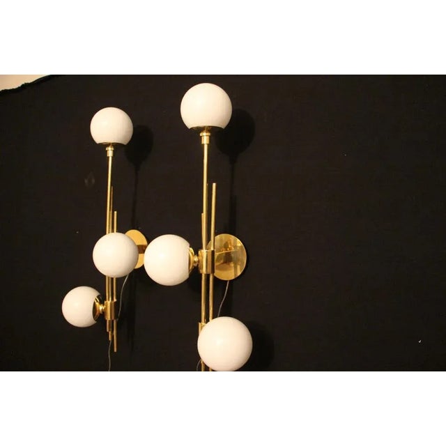 These sconces are very chic with their brass frame and white Murano glass dome. They have got very unusual geometrical...