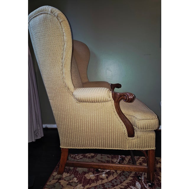 Classic, generously proportioned vintage wingback armchair featuring beautifully carved solid wood arms and legs. The...