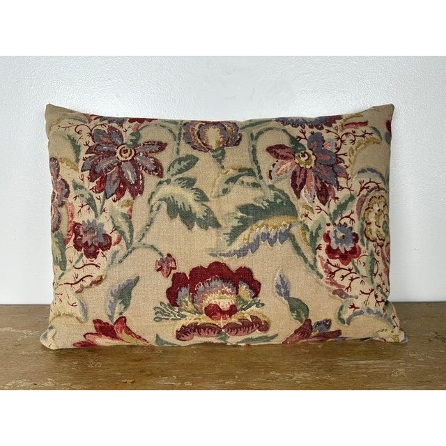 A decorative pillow crafted from a beautifully printed linen textile featuring a lively floral and foliate motif in rich,...
