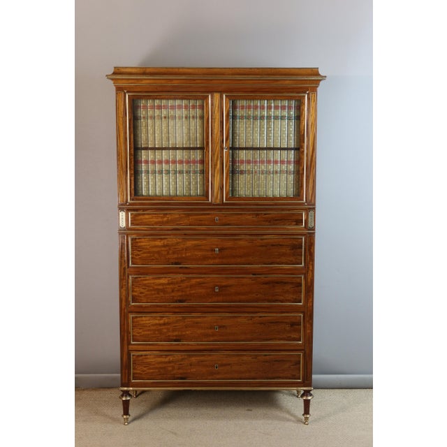 A secretary desk veneered in dark satinwood with brass stringing, it opens with two doors in the upper section, three...