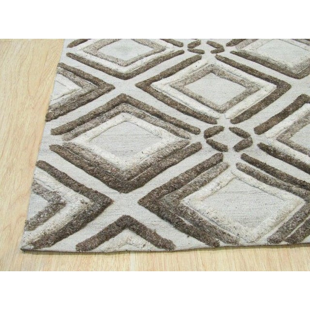 This hand knotted pile rug is crafted from wool and features a primary color palette of ivory, beige, cream, and white....