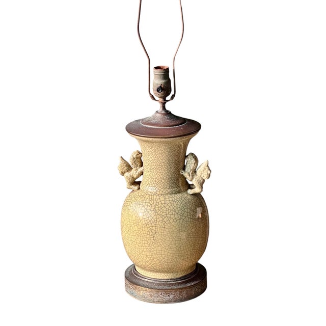 Antique ceramic vase lamp with a warm golden crackle glaze and two sculpted foo dog handles. The base is encircled with a...