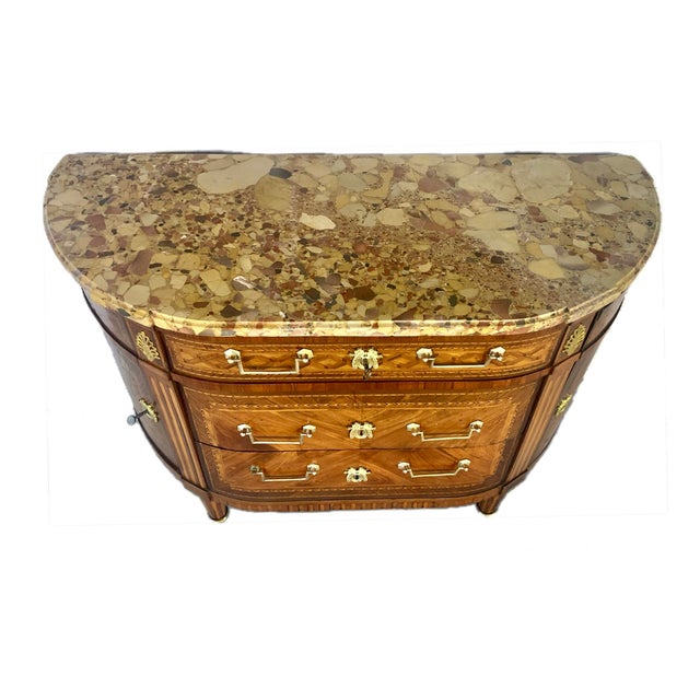 French Louis XVI period commode featuring exquisite geometric parquetry inlay and a richly veined demilune Breche marble...