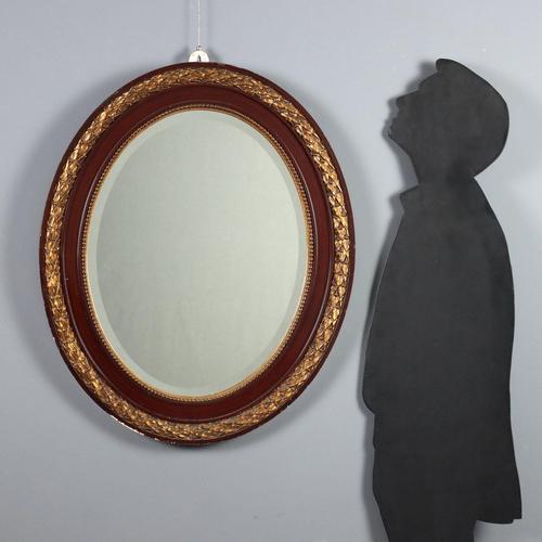 Oval mahogany mirror with gilded carvings. Beveled mirror with ribbed molding and subsequent leaf carvings. Italy, 20th...