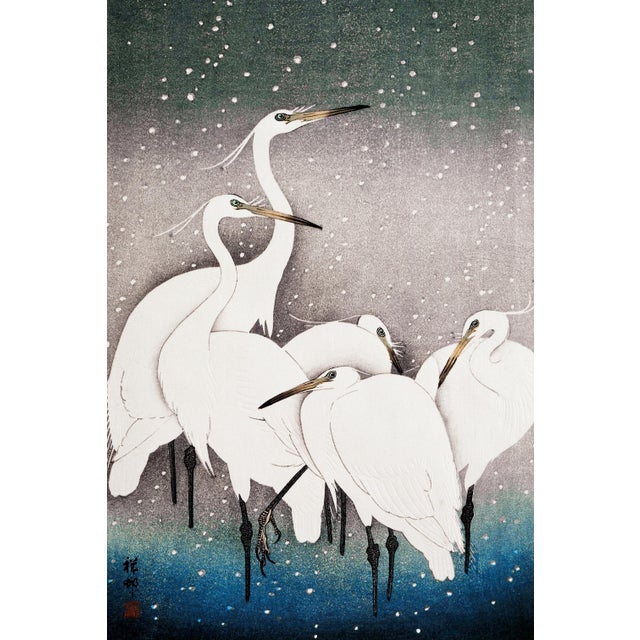 Vintage Japanese bird artwork depicting a quiet grouping of white egrets standing together beneath softly falling snow,...
