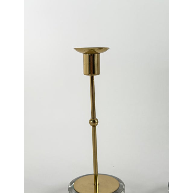 Elegant pair of Scandinavian Modern candlesticks featuring polished brass stems mounted on substantial frosted glass...
