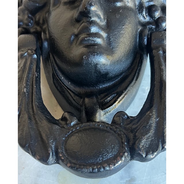 Grecian face door knocker, made of cast iron and painted black.