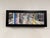 This mixed-media piece combines photography, collage, and acrylic on a panel, creating a dynamic urban scene that captures...