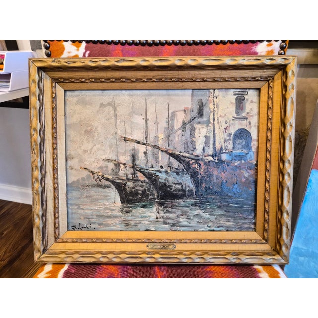 A vintage oil painting by the Italian artist Elio Corsi. It depicts fishing boats docked at a harbor. This is an oil...