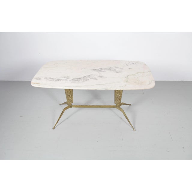 This side table was made in Italy in the 1950s. It features a brass frame with a garland motif and four dainty feet. A...