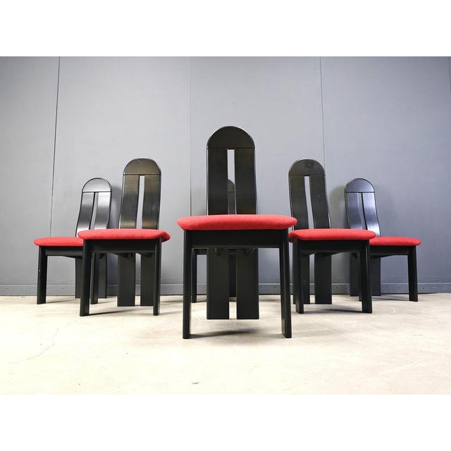 Postmodern design dining chairs with black wooden frames and a striking red fabric cushion. Timeless chairs 1980s -...