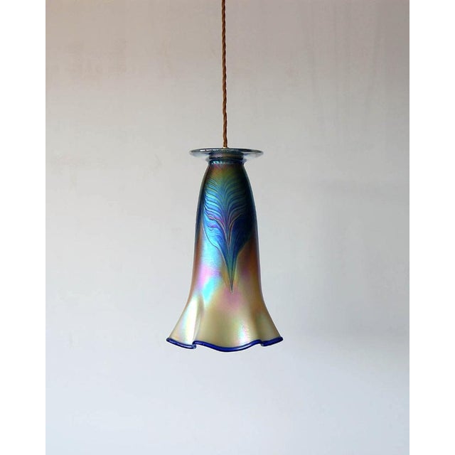 This hand-blown iridescent glass piece in blue, ivory and green tones is decorated with peacock feather geometric decor...