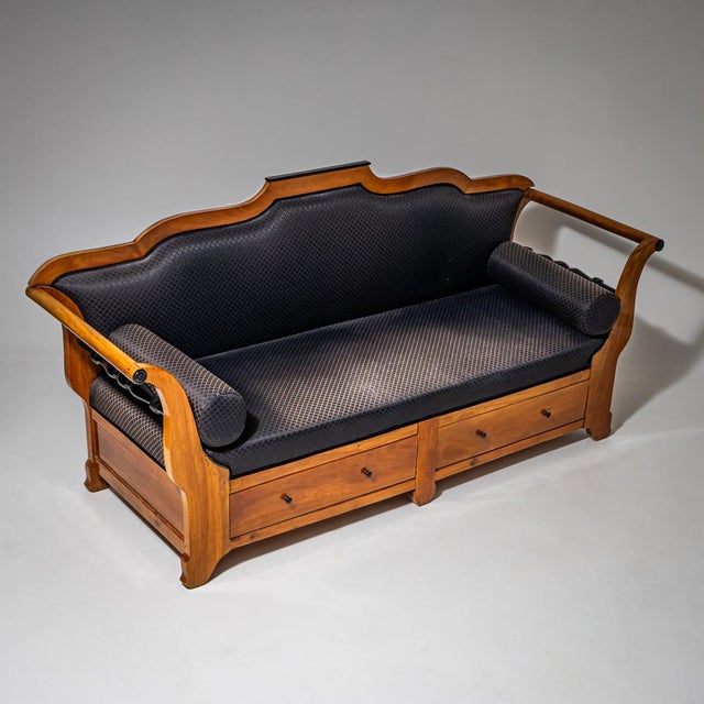 Biedermeier sofa crafted from cherrywood, featuring a multi-curved backrest and sleigh-shaped armrests. Ebonized turned...