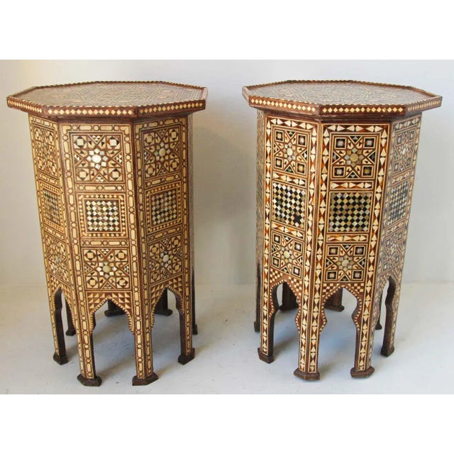 Pair of Moroccan Moorish style walnut octagonal pedestal tables inlaid with mosaic marquetry. Tabletop is of octagonal...
