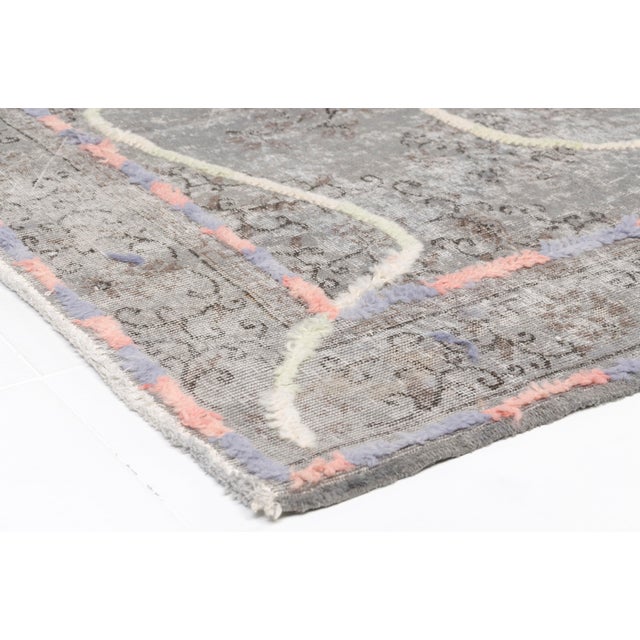 This is a vintage Turkish Oushak rug from the Mid 20th Century. The piece was hand-knotted.