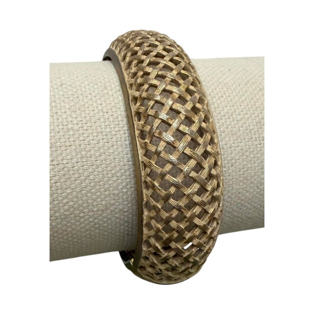 This vintage hinged bangle features a basketweave design and a secure clasp. Gold-tone with cream original patina.