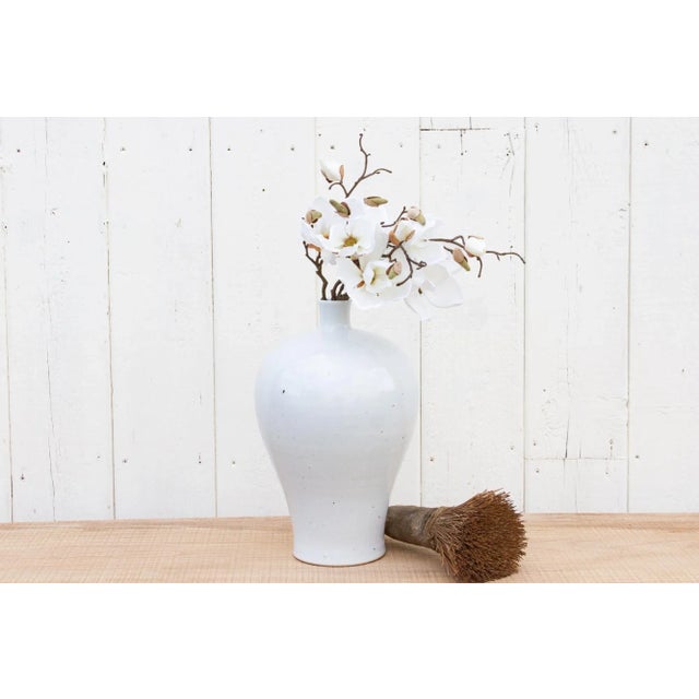 A vintage white glaze Meiping vase from China. Its cool, serene glaze drapes its clean lines like a delicate gown,...