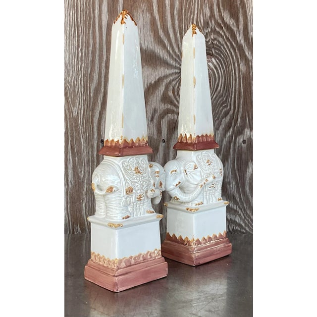 A stunning pair of vintage glazed terra cotta obelisks. A fun elephant design with trunks up for good luck. Acquired from...