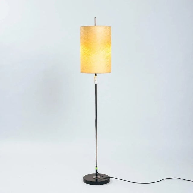 Height-adjustable floor lamp from the 60s. The base is made of black lacquered metal, the steel is made of chromed metal....
