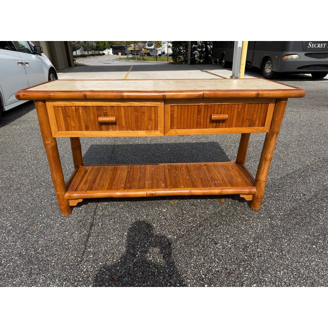 Mid-Century natural bamboo and stone top console table. The bamboo base has a bamboo bottom shelf.and two draws.