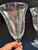 Elegant pair of vintage clear glass wine glasses featuring delicate etched grapevine decoration and graceful tulip-form...