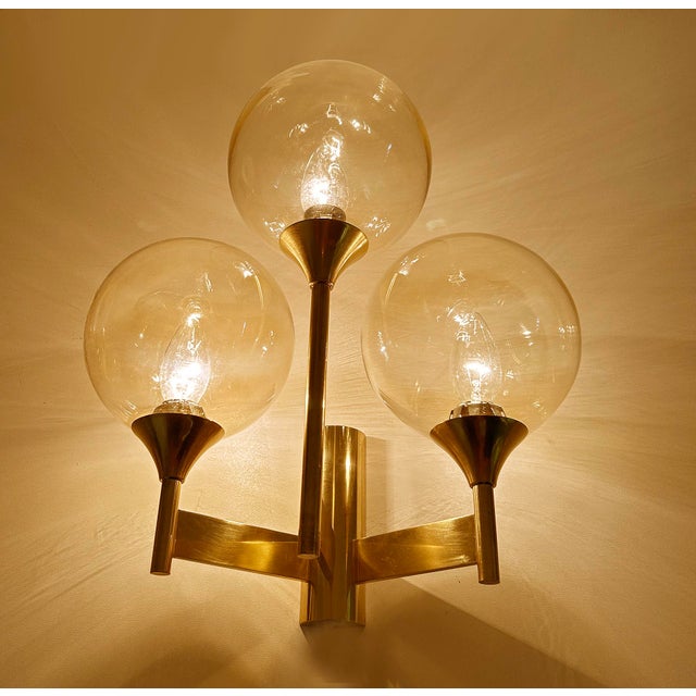 large vintage wall light featuring a bronze and brass structure with 3 spokes and light amber tint glass globe shades...