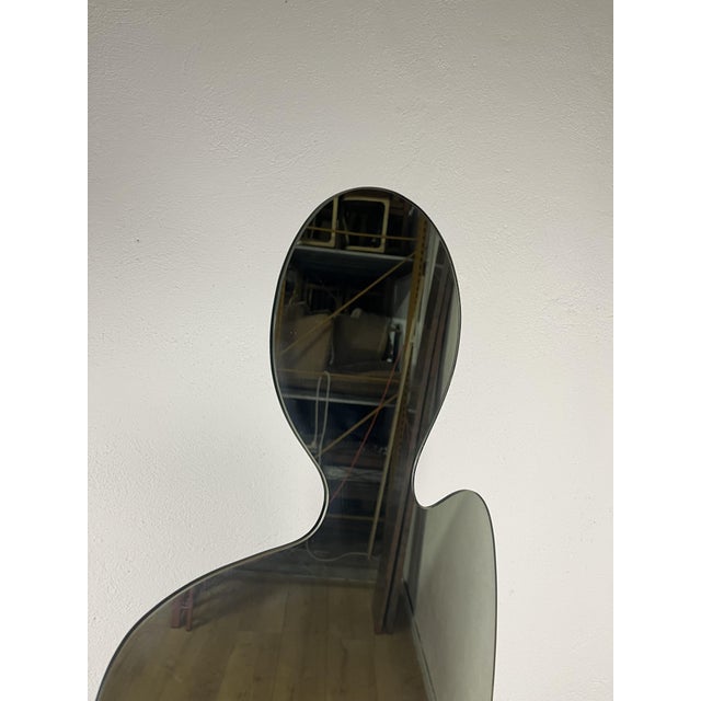 The Narciso floor mirror, featuring an anthropomorphic silhouette in mirrored glass and a pietra serena stone base, was...