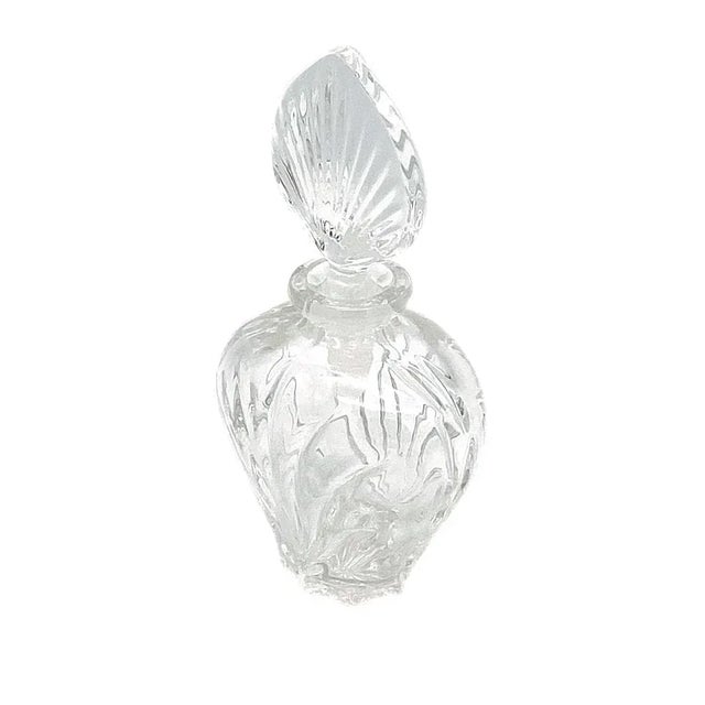 This is a molded clear glass perfume bottle with an elegant shaped body and a fan shaped stopped.
