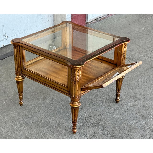 This giltwood vitrine table is glazed on the top and all four sides, and the front panel drops down on hinges so you can...