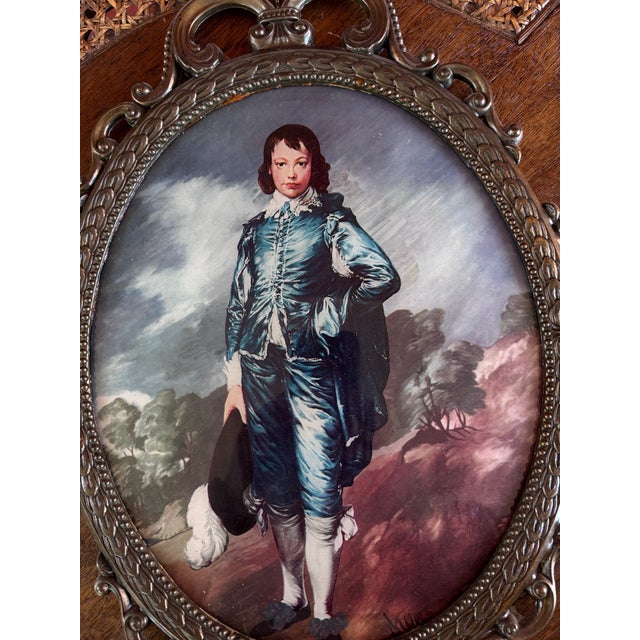 This is a vintage reproduction of Thomas Gainsborough’s “The Blue Boy,” displayed beneath convex glass in an ornate brass-...