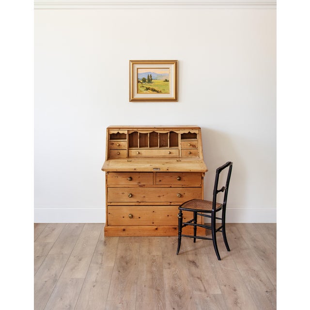An English country pine bureau in the Georgian tradition, with the classic slant-front form that opens onto a working...