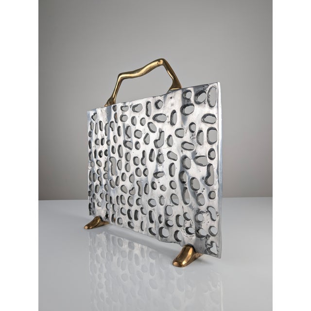 This spark guard is a sculptural work made of brass and aluminum, reflecting a Brutalist aesthetic. The piece features the...
