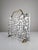 This spark guard is a sculptural work made of brass and aluminum, reflecting a Brutalist aesthetic. The piece features the...